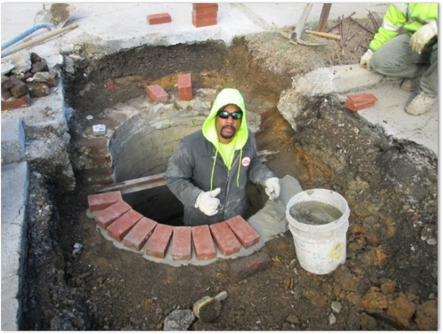 A worker repairing a storm sewer inlet.