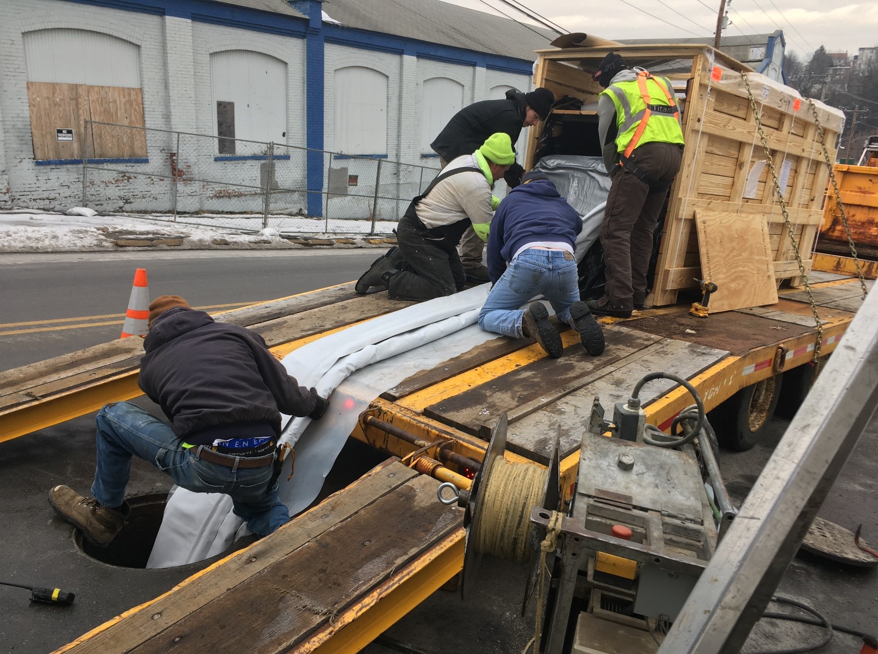 Workers adding new protective sleeve to stormwater pipes underground.